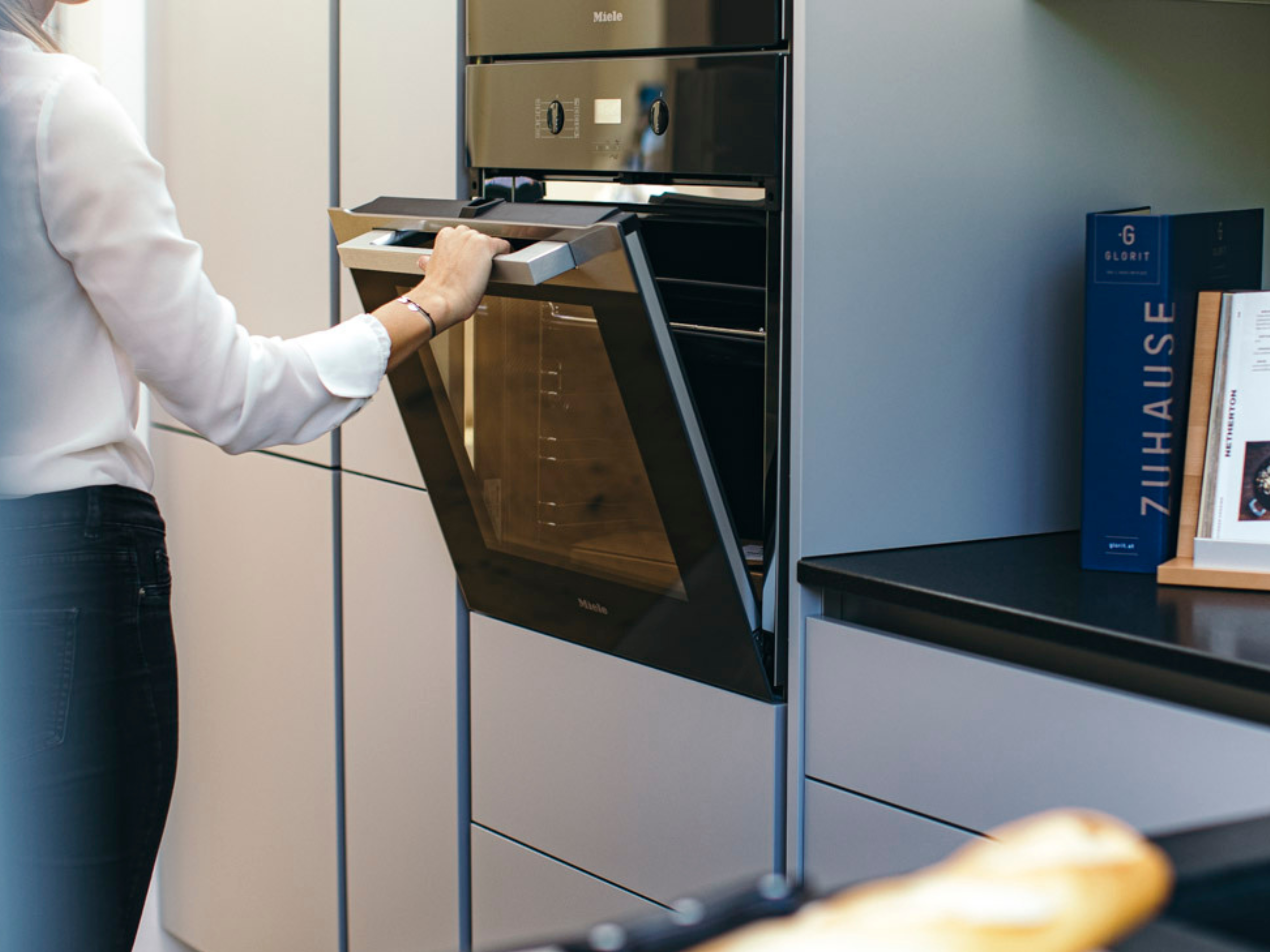 Frau steht in einer Küche und öffnet Backofen